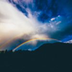 Rainbow over a dark hillside, reflecting on Jesus, the Last Adam, who gives eternal life through His life-giving Spirit.