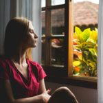Woman sitting quietly by a window, reflecting on Jesus, the prince of peace, who gives peace in every circumstance.