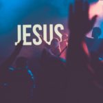 Worship gathering with hands raised before the name Jesus, reflecting on Christ as the Name Above All Names.