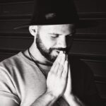 Man praying with hands together, reflecting on our Father in heaven who loves us, hears us, and is always near.