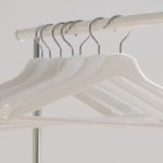 Minimalist white hangers on a clothing rack, symbolizing how God Is Our Clothier and clothes us with Christ’s righteousness.