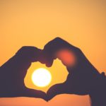 Hands forming a heart around the sun symbolizing how God Demonstrates His Love through the sacrifice of Jesus Christ.