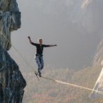 Person balancing on a tightrope between cliffs illustrating feeling weak and teetering under spiritual attack and trusting that The Lord Is My Defender.