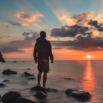 Person standing at the shore at sunset, reflecting on Jesus as the Guilt Offering who took our sin and brings forgiveness and peace