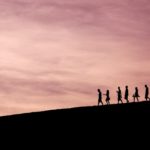 Silhouettes walking in line at sunset, illustrating following Christ as the Head of Every Man and living in step with His leadership