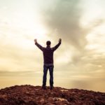 Person standing with arms raised toward the sky, praising God Our Healer who brings hope, restoration, and eternal healing.