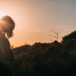 Pregnant woman silhouetted at sunset, reflecting the coming of Immanuel God With Us through the birth of Jesus.