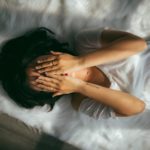 Person lying in bed overwhelmed with emotion, reflecting the comfort of knowing God has Infinite Understanding and fully knows our hearts and struggles.