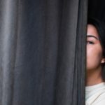 Woman peeking from behind a curtain, reflecting on how God Is Just and sees every heart and motive.