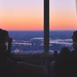 Two people looking out over a vast landscape at sunset, reflecting on God as the possessor of heaven and earth.