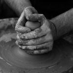 Hands shaping clay on a pottery wheel, reflecting on God as the potter who lovingly molds and shapes our lives.