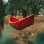 Red hammock hanging between trees, illustrating Sabbath rest and the invitation to slow down and find rest in Jesus.