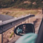 Woman checking the road behind her in a side mirror, illustrating how God is my rear guard who watches over and protects me.