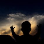 Silhouette of a person with hands raised, representing gratitude that Jesus is my ransom who gave Himself to free me from sin.