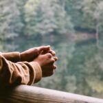 Person standing quietly with hands clasped, reflecting on Jesus as the Son of the Blessed One and the security of our identity in Him.