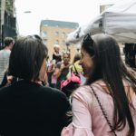 Two women talking in a busy public setting, illustrating how the world changes while Jesus is the same yesterday, today, and forever.