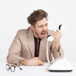 Man yelling into a telephone, illustrating the struggle with our sinful nature and our need for God our sanctifier to transform us into Christ’s image.