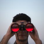 Man looking through binoculars, representing the hope of looking ahead to Jesus our redeemer and the eternal life He promises.
