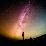 Person standing under a star-filled sky, reflecting on how the Invisible God reveals His glory through creation.
