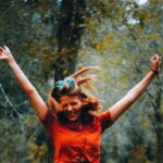 Woman joyfully lifting her arms outdoors, reflecting on God’s Lavish Grace that brings forgiveness, redemption, and lasting joy.