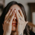 Woman covering her eyes, reflecting uncertainty and the invitation to trust Jesus as the resurrection and the life.