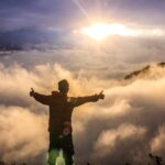 Person standing with arms raised toward the light, reflecting on the truth that God is a rewarder of those who seek Him in faith.