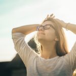 Woman resting in sunlight, reflecting on Jesus and the oil of gladness He gives through the Holy Spirit.