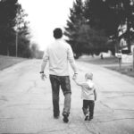 A loving father holding the hand of his child, symbolizing God's care for His children.