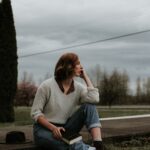 Woman sitting outdoors on a ledge holding a Bible and reflecting thoughtfully, illustrating the theme of Wonderful Counselor and seeking God’s guidance.