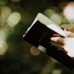 Person holding a Bible representing faith in Jesus Our Deliverer who rescues from sin, evil, and fear.