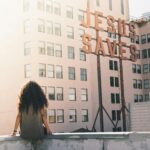 Person looking toward a “Jesus Saves” sign, reflecting faith in the Immutable God whose truth and salvation never change.