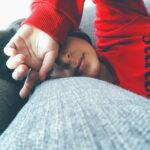 Tired person resting on a couch, illustrating the need for God our refresher to renew weary hearts and restore strength.