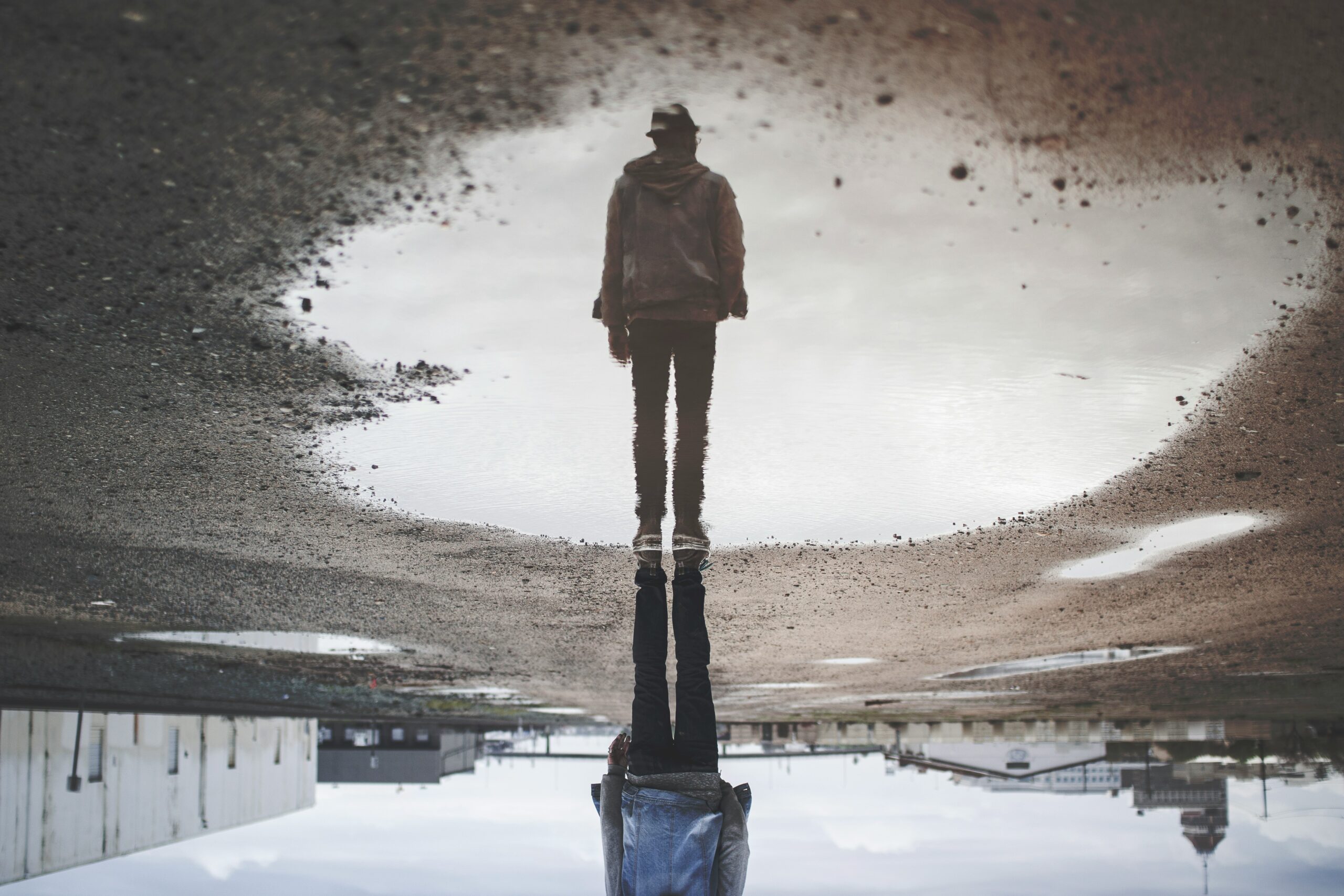 The reflection of a man in a puddle.