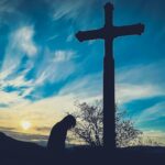 Person kneeling at the cross, reflecting repentance and the mercy of our Gracious God who forgives and restores.