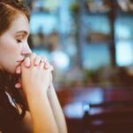 Woman praying quietly, reflecting on the Lord’s patience and how He is not wishing for any to perish.