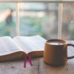 Open Bible beside a cup of coffee, illustrating how we can bask in the truth that God is resplendent by reading His Word.