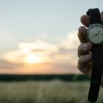 Hand holding a watch at sunset, reflecting on God as the one who appoints people, places, and times.
