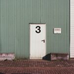 Door marked with the number three, reflecting on how Jesus is called the alpha and omega three times in Revelation.