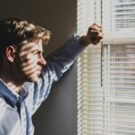 Man looking through blinds, reflecting on guilt and forgiveness through Jesus, the Innocent Savior.