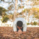 Person kneeling in reverence and prayer, reflecting awe before the Holy, Holy, Holy Lord whose glory and holiness inspire worship.