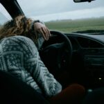 Woman resting in a car on a dreary day, reflecting on the King of Glory who fills believers with His presence.