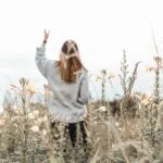 Woman worshiping in a field, drawing near to the Intimate Lord who offers His presence and private counsel.