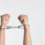 Hands in handcuffs, reflecting on God who loosens bonds and sets us free through His power.
