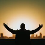 Silhouette of a person with arms raised, praying to the Lord Our God who is near and hears our prayers.