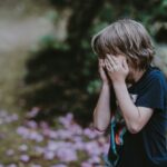 A child covering his eyes while playing hide and seek outdoors, illustrating the message of the Second Coming of Jesus and the need to be spiritually ready.