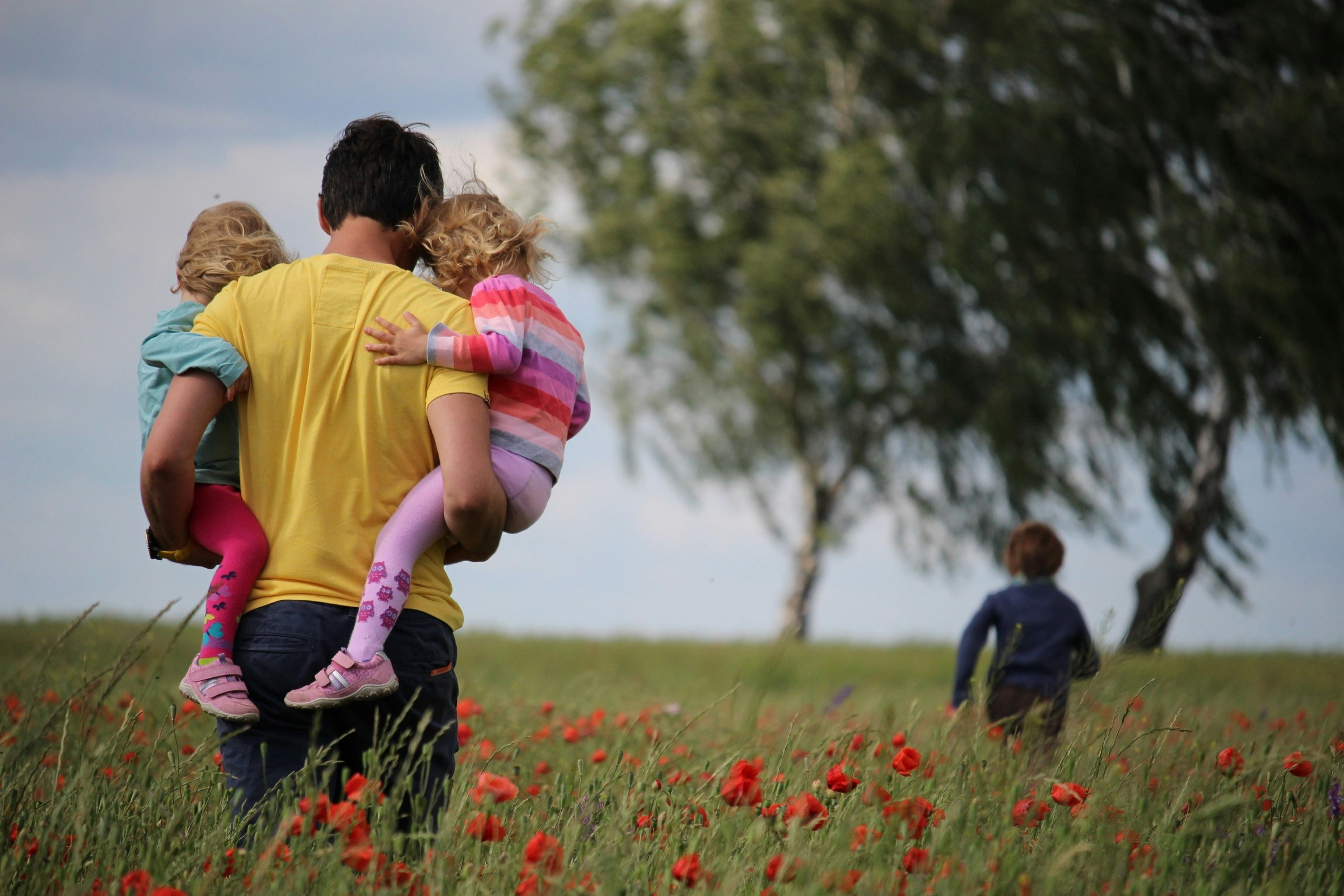 Father carrying his children across a field illustrating how The Father Delights In Jesus and lovingly delights in His children.