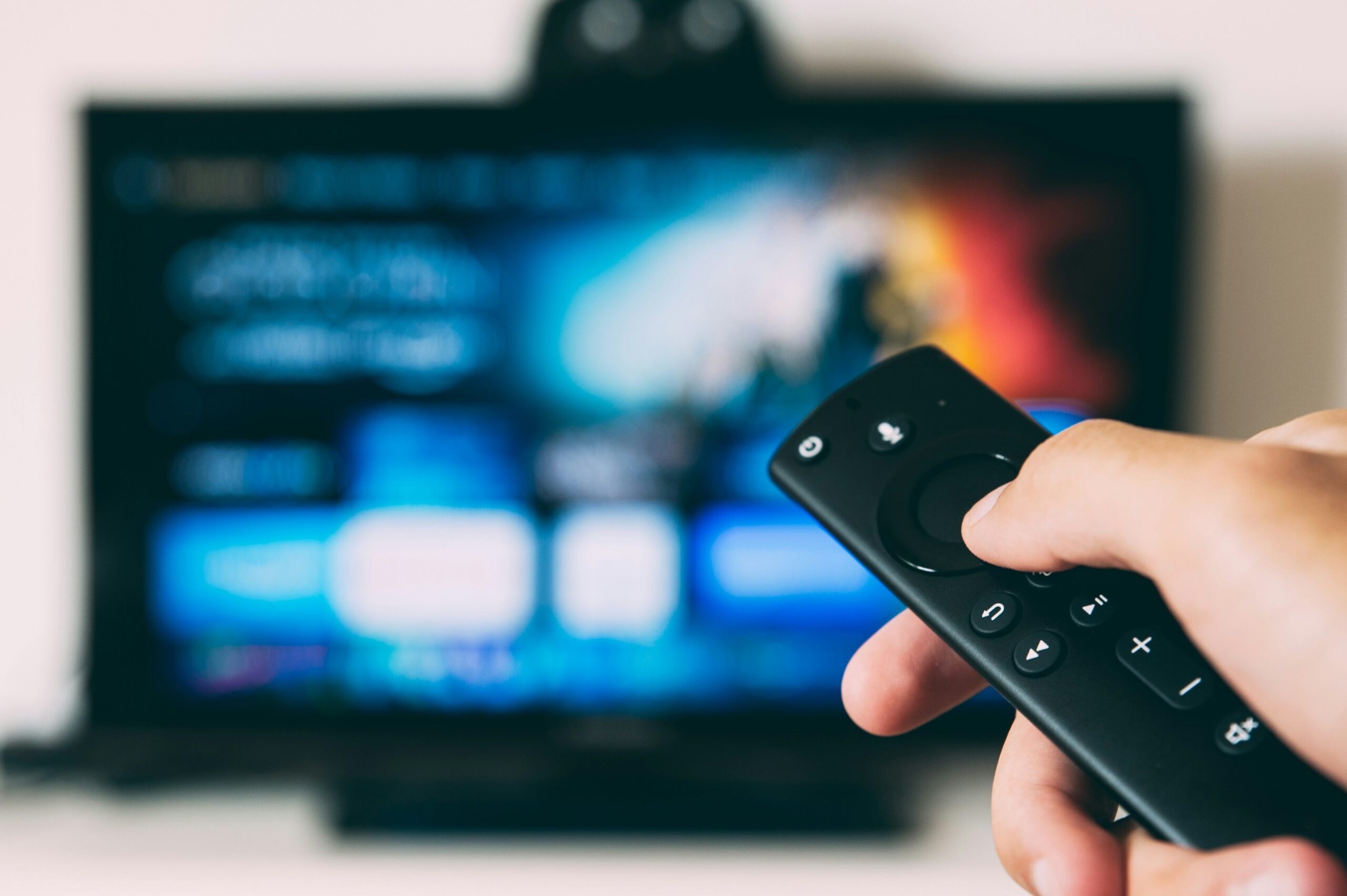 Hand holding a TV remote in front of a television, illustrating the need to stand against pornography and harmful media content.